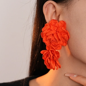 Close-up of orange fabric handmade double flower earrings on model with soft lighting