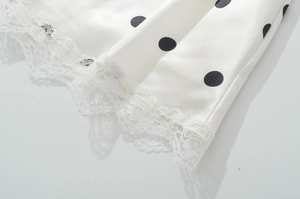 Detail of the white satin hem with black polka dots and delicate lace trim edge