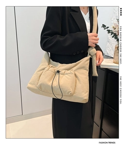 Detailed shot of beige nylon crossbody bag with drawstring pocket and wide shoulder strap