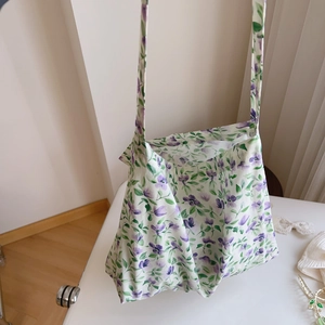Detail of a large cotton tote bag featuring purple and green floral prints with long straps