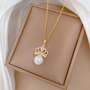 Detailed close-up of crown pearl pendant with gold chain on white silk background