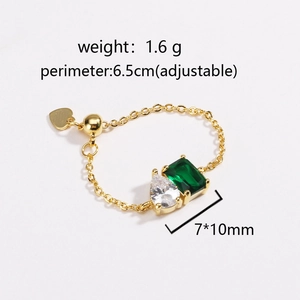 Close-up of gold ring with rectangle emerald zircon and pear-shaped clear stone