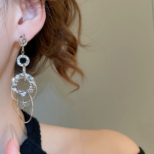 Close-up of model wearing silver knotted earrings with interlocking textured rings