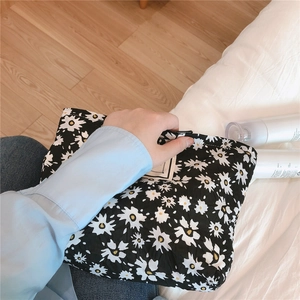 Detailed close-up of a black floral puff fabric cosmetic bag with daisy prints