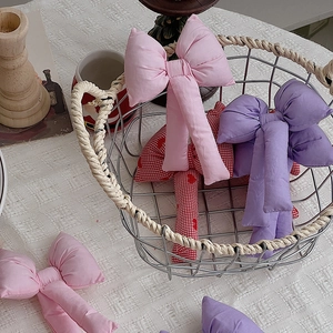 Fiocchi di Natale imbottiti in rosa, viola e scacchi rossi su tovaglia bianca morbida