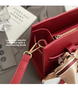 Détail d'un sac à main en cuir rouge avec ferrures dorées et foulard en soie