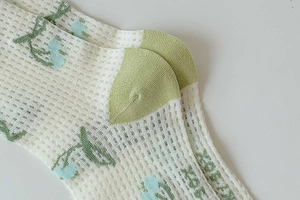 Detailed macro view of floral mesh breathable socks with XOXO pattern and green heel