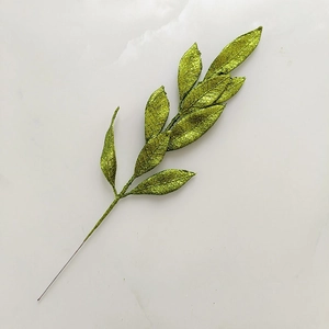Detail of green glitter artificial Christmas tree branch on white marble surface