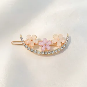 Detail of crescent hair clip with frosted flowers and sparkling crystals on silk background