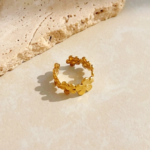 Fashionable 18K gold-plated stainless steel flower ring on a natural stone background