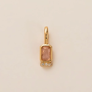 Detailed view of gold pendant featuring a peach gemstone and white accent stones