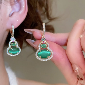 Detail of 14k gold plated wulu earrings with green cat-eye stones and cubic zirconia