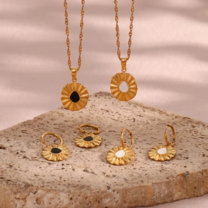 Golden jewelry set featuring wavy edge necklaces and earrings with black and white enamel
