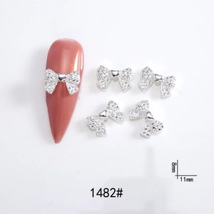 Macro shot of silver bow nail art charms with crystals, 11x8mm size for manicure