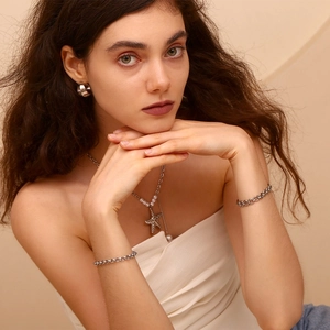 Close-up of a silver chunky chain bracelet and starfish pearl necklace on a model