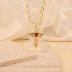 Golden cross sword necklace with red gemstone and snake chain on marble stone background