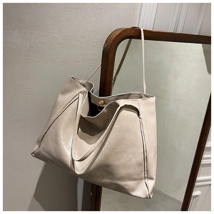 Detail of beige large capacity faux leather tote bag with magnetic clasp on a mirror frame