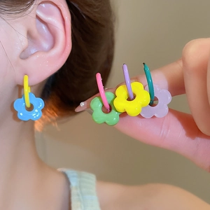 Close-up of colorful flower charm hoop earrings in vibrant blue, green and yellow colors