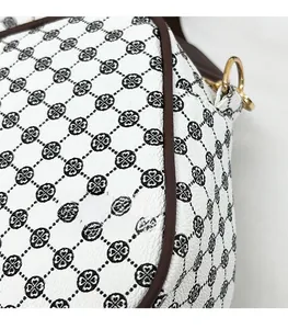 Macro detail of white leather shoulder bag with clover pattern and gold metal D-ring