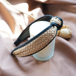 Close-up of hand-woven raffia headband with black fabric knot on white candle holder
