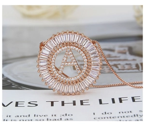 Macro detail of rose gold letter A pendant necklace with baguette and round zircons