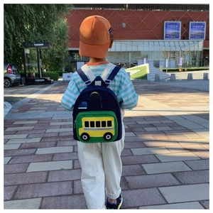 Blue school backpack with a yellow bus design worn by a child in an outdoor setting