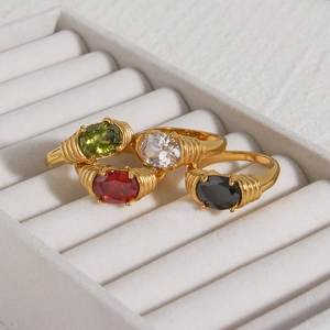Close-up of gold-plated rings with ribbed bands and colorful oval zircon stones