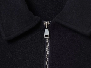 Détail du revers et de la fermeture éclair en métal argenté sur un manteau en laine noir