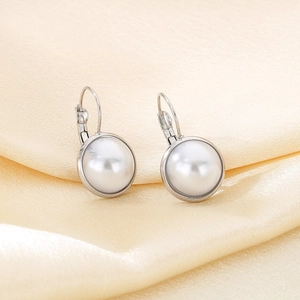Macro shot of silver lever-back earrings with white shell pearls on silk fabric