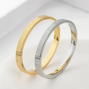 Detail of gold and silver steel bracelets with Jesus engraving and Greek key pattern