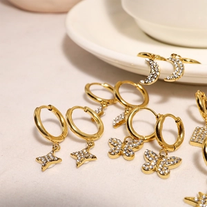 Detailed macro view of gold-plated hoop earrings with star, butterfly, and moon charms