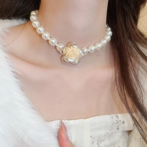 Detail of multi-layer pearl necklace with a diamond-encrusted camellia flower pendant
