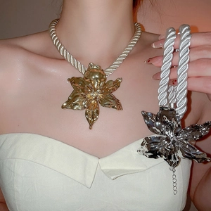 Detailed view of metallic flower necklace set in gold and silver on a white braided cord