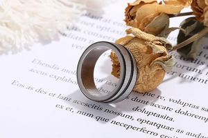 Detailed shot of brushed stainless steel ring with black groove line on paper background