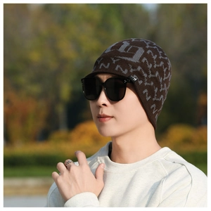 Close-up of deep coffee knit beanie with grey jacquard patterns and a short sun visor