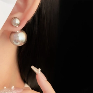 Macro view of double-bead pearl earrings in metallic silver finish worn by model