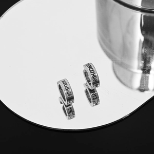 Silver stainless steel rune ear clips with Nordic engravings reflected on a mirror