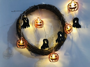 Detail of warm glow LED pumpkin and ghost lights wrapped around a rustic vine wreath