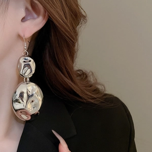 Close-up of elegant irregular silver wrinkled drop earrings worn by a model in luxury style