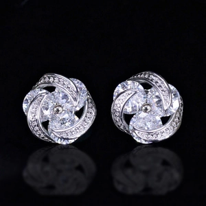 Silver flower stud earrings with brilliant zircon stones on reflective black background