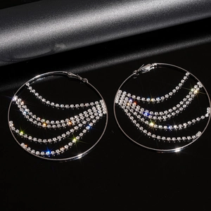 Detailed shot of silver hoop earrings with shimmering rhinestone tassels on a black base