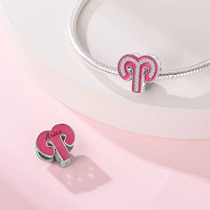 Macro shot of silver Aries charm with pink enamel and crystals on a snake chain bracelet