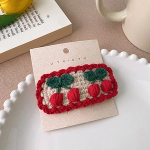 Détail d'une barrette cerise crochetée main avec vagues rouges sur base crème