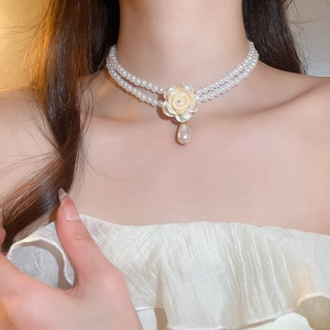 Détail du collier de perles double rang avec pendentif fleur blanche et goutte de perle