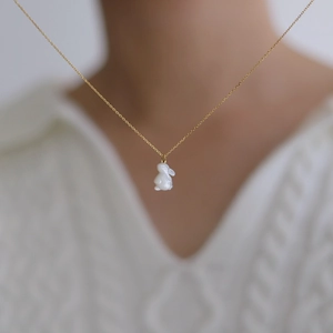 Détail d'un collier avec pendentif lapin en nacre blanche sur une chaîne dorée