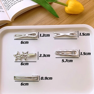 Detailed size view of silver Y2K metal hair clips in star and bow shapes on a tray