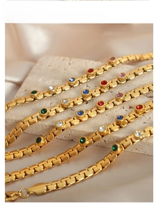Close-up of gold box chain bracelet featuring vibrant multi-colored crystal stones