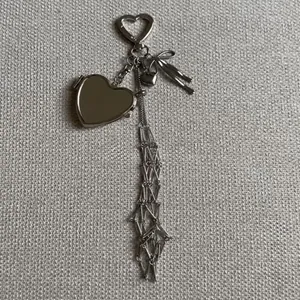 Silver heart-shaped keychain pendant with bow and long metal tassels on grey texture