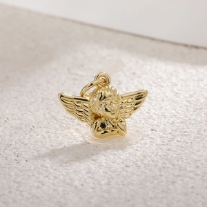 Macro shot of a gold-plated cupid angel wing pendant on a white stone background