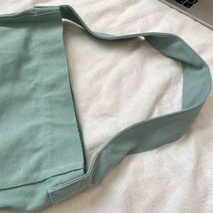 Dettaglio borsa a tracolla in tela verde menta con tracolla larga e trama resistente